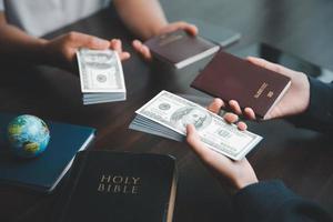 Concept of Christian ministry. Small groups pray together for Christian mission. Mission to spread gospel and religion of Christianity around world. Hands holding dollar and passport on wooden table. photo