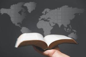 Hand holding Holy Bible and world map in blur background. World mission christian idea. Copy space for text. Christian background for great commission or earth day concept. photo