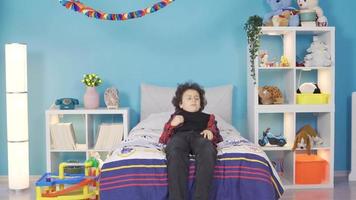 Curly-haired smart boy finds a new idea and rejoices. The boy lying in his bed has a new idea or invention in mind, and he suddenly gets up and rejoices. Creative and dreamy. video