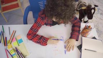 pequeno Garoto desenha uma cenário em papel com colori lápis. a criança desenha uma criativo cenário usando dele imaginação. video
