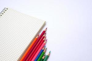 Graph book with colored pencils or pastel lined up on white background. Learning, study and presentation concept. photo