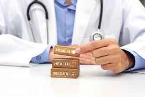 Hand holding a wooden block cube the top one with word and icon symbol. Medical and health concept. photo