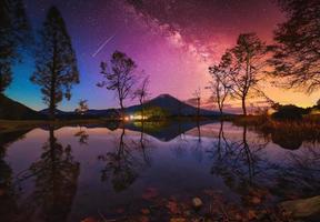 Landscape with Milky way galaxy. Mt. Fuji over lake with big trees and milky way at sunrise in Fujinomiya, Japan. photo