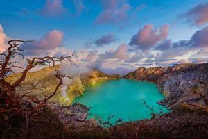 Kawah Ijen volcano with Dead trees on blue sky background in Java, Indonesia.