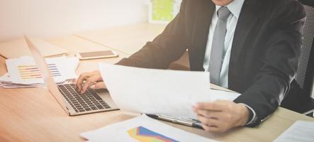 Business man working with laptop and document  on his desk in office. Vintage tone photo