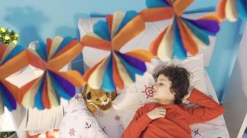 Boy lying in his bed daydreaming and talking with his toy plush. Daydreamer. Boy muttering to himself thinking about his dreams and talking to his toy dog. Children's room. video