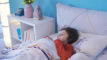 A boy having a nightmare wakes up from the bed in fear. The boy lying alone in the room has a terrible nightmare and suddenly wakes up from the dream. video