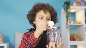 The child puts the bitcoin into the piggy bank and is happy. Child saves money in piggy bank for his future and dreams. The family is investing in their children. video