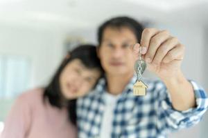 Moving house, relocation. Couple hold key house keychain in new apartment, inside the room was a cardboard box containing personal belongings and furniture. move in the new apartment or condominium photo