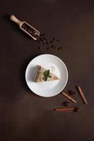 Top view of Layered Cake with cream Napoleon with mint on Brown background. A cinnamon stick, badyan, coffee beans on a brown background. Copy space photo