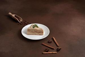 Layered Cake with cream Napoleon with mint on Brown background. A cinnamon stick, badyan, coffee beans on a brown background. Copy space photo