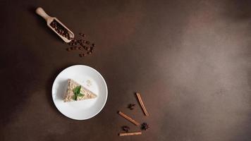 Top view of Layered Cake with cream Napoleon with mint on Brown background. A cinnamon stick, badyan, coffee beans on a brown background. Copy space photo