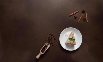 Top view of Layered Cake with cream Napoleon with mint on Brown background. A cinnamon stick, badyan, coffee beans on a brown background. Copy space photo