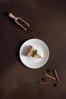 Top view of Delicious Napoleon Cake with cream on a white plate decorated with a sprig of mint on a Brown Background. A cinnamon stick, badyan, coffee beans on a brown background. Copy space photo