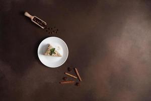 Top view of Layered Cake with cream Napoleon with mint on Brown background. A cinnamon stick, badyan, coffee beans on a brown background. Copy space photo