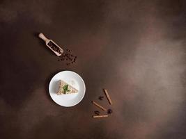 Top view of Fresh delicious Cake Napoleon with cream on a Brown Background. A cinnamon stick, badyan, coffee beans on a brown background. Copy space photo