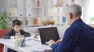 werken vader en leerling zoon werken Bij huis. vader en zoon Bij huis, de kind trekt, en de vader werken met een laptop. video