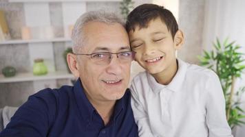 Porträt von glücklich Vater und Sohn. Selfie, Vater und Sohn nehmen Foto. Vater und Sohn suchen beim das Kamera sind nehmen Bilder beim heim. video