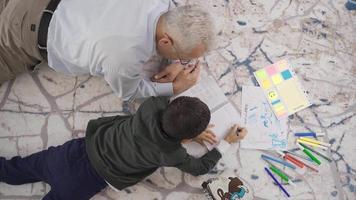 Vater und Sohn zeichnen Bilder und tun Hausaufgaben beim heim. Vater hilft seine Sohn mit Hausaufgaben und Sie verbringen Zeit zusammen. video