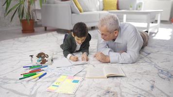 padre e figlio studia insieme a casa. padre porzione il suo alunno figlio con compiti a casa. video