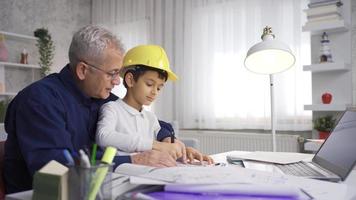 ingénieur père travaux à Accueil avec le sien fils. le fils, qui porte le sien du père casque, travaux ensemble à maison. video