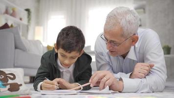 Positive father loves his son and helps him with his homework. Dad is proud of his son and kisses him on the head. video