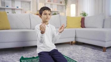 musulmán chico Orando a hogar con abierto manos. musulmán chico Orando. video