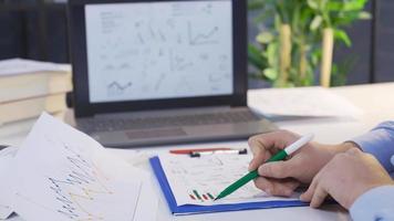 Analyzing charts. Financial Data, Reading. Businessman working with analysis chart and using laptop. video