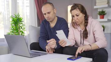 The couple makes calculations at home with a calculator and looks at the bills. Working married couple trying to pay the bills. video