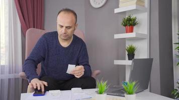 bezorgd Mens ten gevolge naar financieel problemen op zoek Bij rekeningen en bank schulden. Mens aan het doen financieel berekening in huis economie is in schuld en wanhopig. video