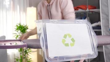 reciclar compartimiento. reciclaje a hogar. Respetuoso del medio ambiente mujer lanza ropa en reciclaje compartimiento. video