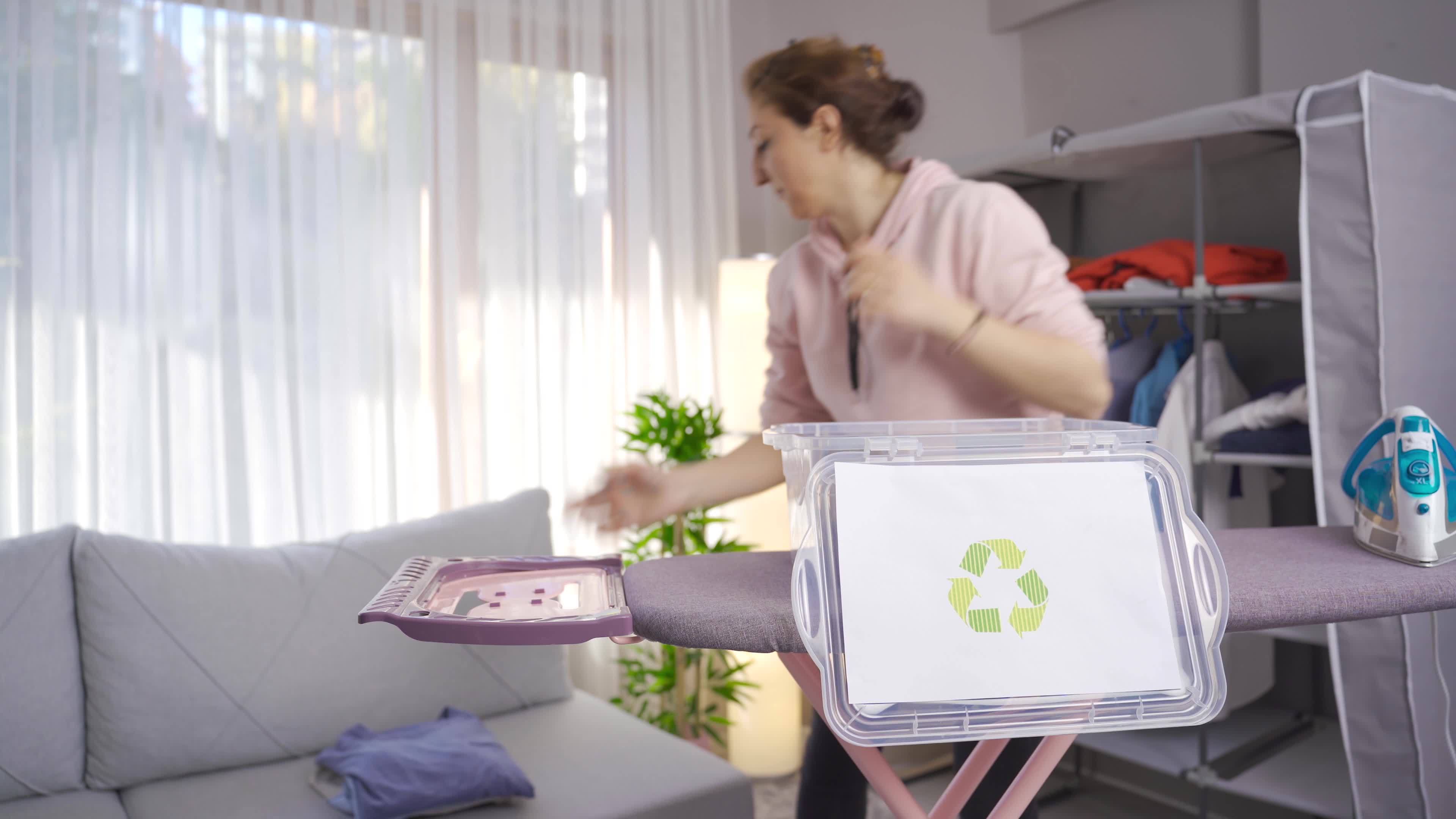Ecofriendly woman throws clothes in recycling bin. Woman puts clothes