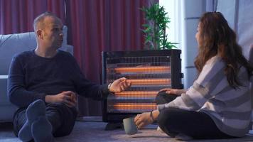 de koud paar zijn opwarming zich door de elektrisch verwarming. de verkoudheid paar is opwarming zich met de elektrisch verwarming, chatten en nippen hun koffie. video