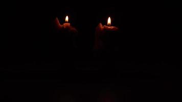 zwei Kerzen auf schwarz Hintergrund. Beleuchtung Kerzen im Dunkelheit. Gelb Wachs Kerze mit warm Flamme. video