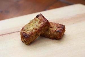 a close up of fried tempeh on a wooden cutting board photo