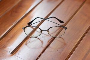 a close up of eyeglasses with black frames isolated natural patterned wooden background. photo