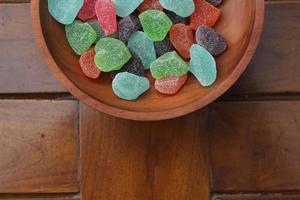 a close up of gummy candies of various colors and fruit flavors served in a wooden bowl. photo