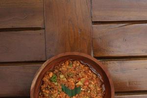 a close up Rujak Bebek or smashed fruit which is made from raw fruit crushed in a mortar and pestle and added with shrimp paste, chili and brown sugar. Indonesian traditional food photo concept.