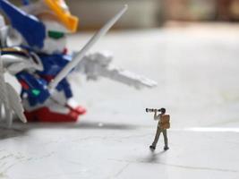 miniatura figura de un fotógrafo tomando un foto de un robot.