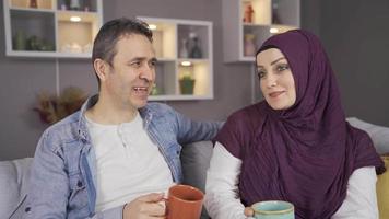 Happy Muslim woman in hijab and her husband at home. Happy Muslim couple having intimate conversation at their home.