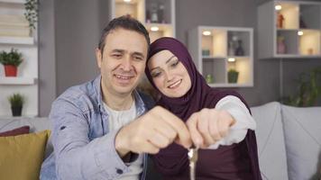Muslim woman in hijab and her husband become house owners, house keys. The Muslim family becomes the home owner. video