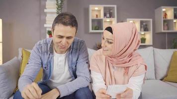 moslim paar berekenen huishouden begroting en schuld rekeningen. moslim volwassen paar bespreken betalingen, berekenen rekeningen samen gebruik makend van laptop en telefoon. video