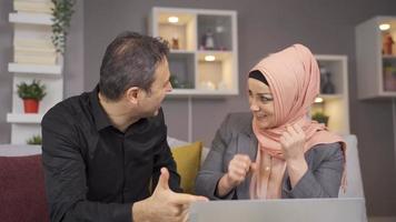 Muslim husband and wife rejoice. Receiving good news. The Muslim couple sit on the sofa at home and rejoice at the news. video