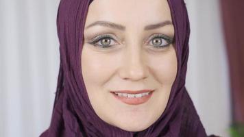 retrato do muçulmano mulher. ele é olhando às a Câmera e sorridente. colorida olhos mulher dentro hijab é olhando às Câmera e sorridente. video