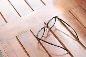 a close up of eyeglasses with black frames isolated natural patterned wooden background. photo