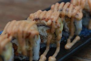 japonés comida llamado salmón queso mozzarella Sushi. servido calentar en un negro rectangular plato en el mesa. foto