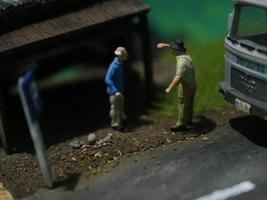 a close up of a miniature figure of an old man talking to other people in an old building by the side of the road. photo