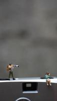 a miniature figure taking picture with a camera against a real camera in the background. photo
