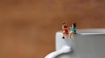Miniature figures of 2 women talking over glasses. discussion concept. photo