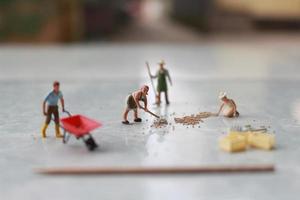 miniatura cifras de trabajadores trabajando juntos a moverse grano. foto